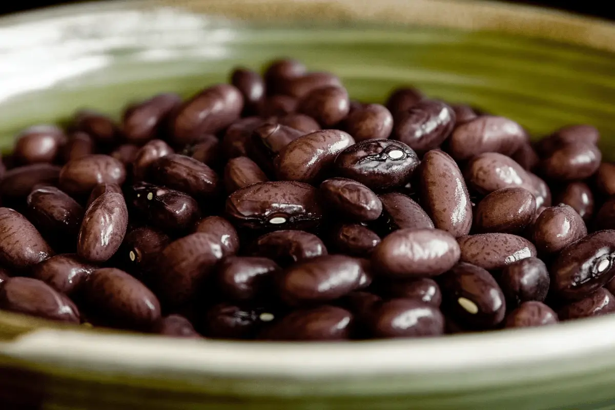 Cooked black beans showing a subtle purple tint in a ceramic bowl.